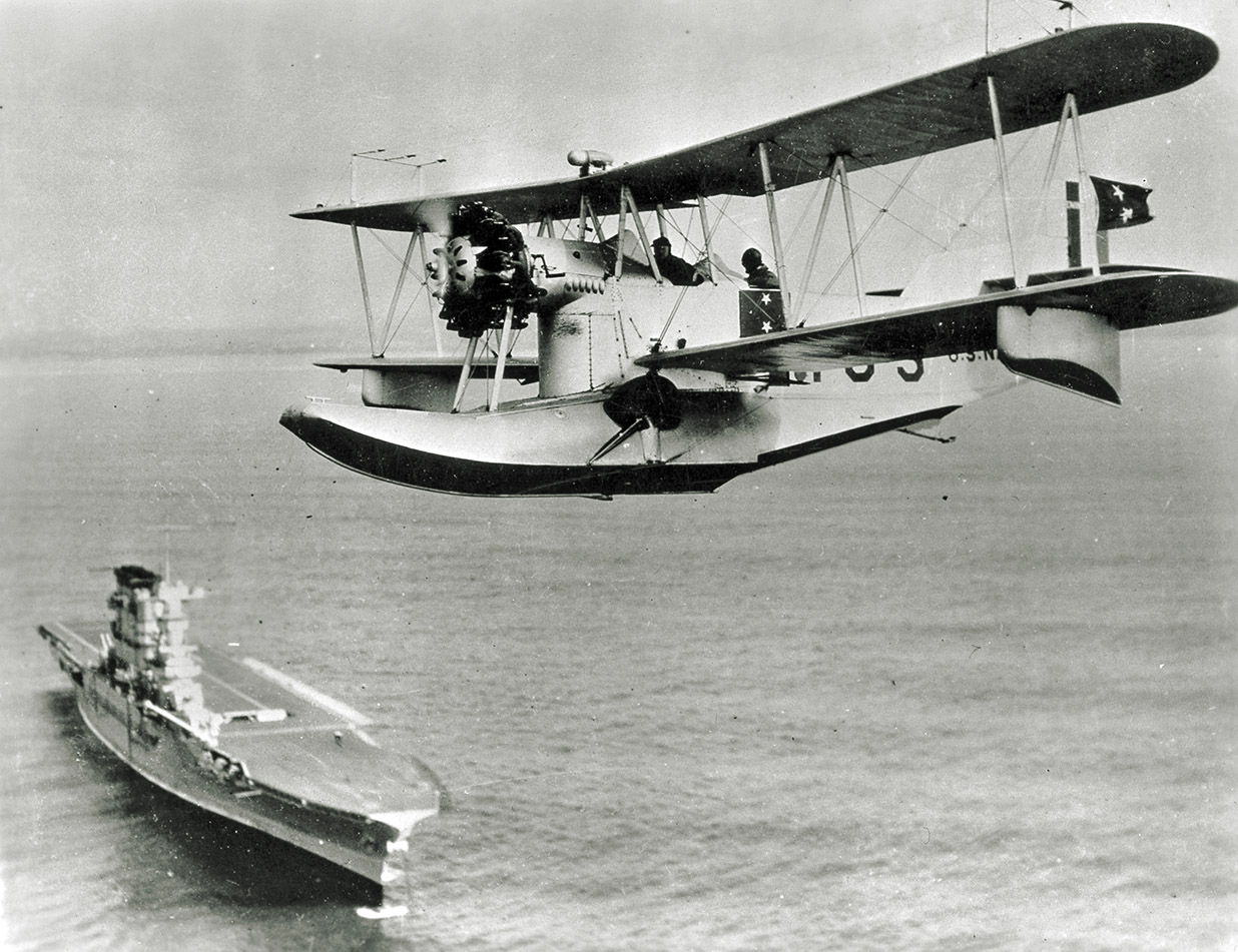 A Loening OL seaplane flies over USS Lexington (CV 2). A Loening OL seaplane flies over USS Lexington (CV 2).